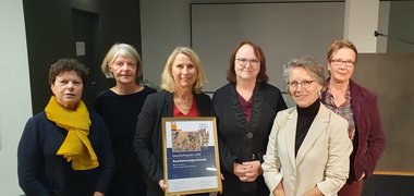 Sechs Frauen auf einem Gruppenfoto mit Preisurkunde